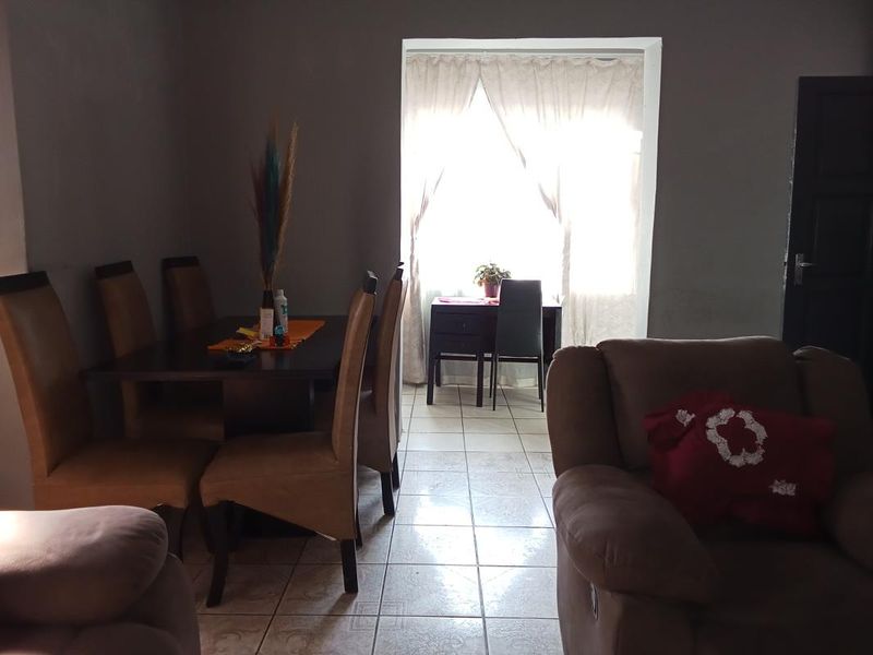 A living area featuring tiled flooring and a large window with curtains, providing natural light to the space.