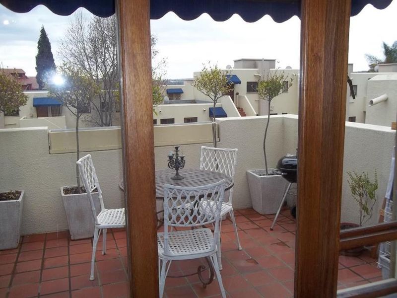 A private balcony featuring terracotta tiling, a parapet wall, and a retractable awning, offering an outdoor space for relaxation.
