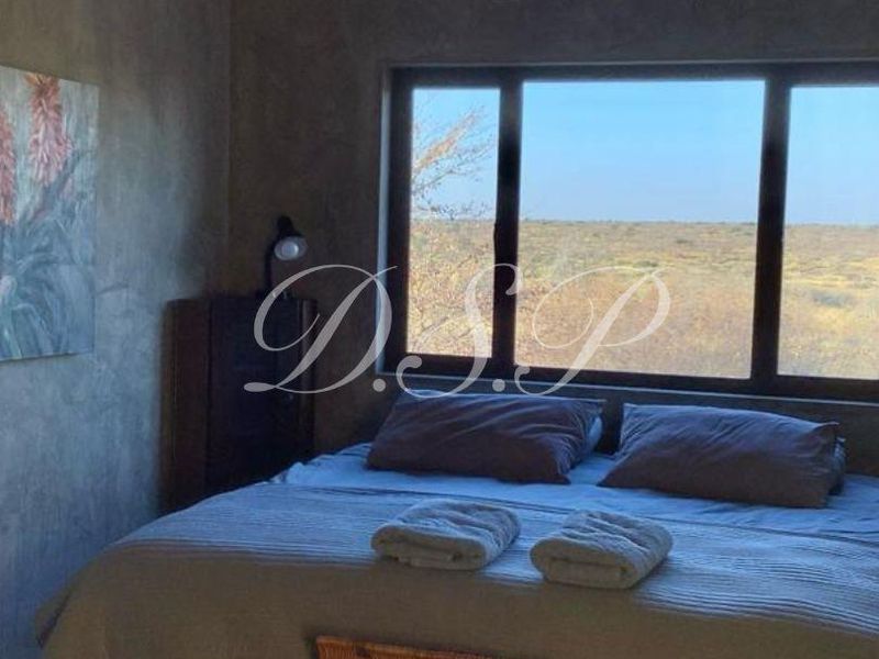 A bedroom featuring a unique corrugated metal ceiling, a ceiling fan, and a large window offering expansive views of the surrounding landscape.