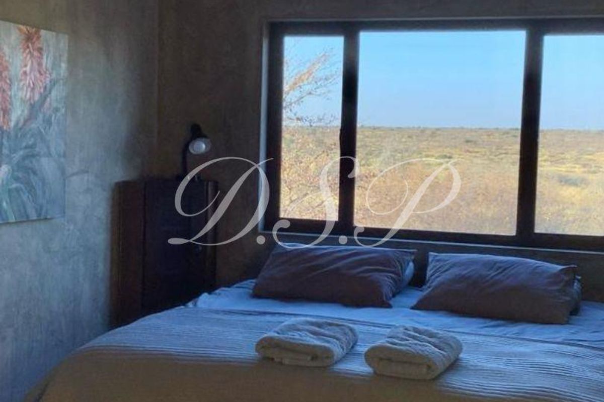 A bedroom featuring a unique corrugated metal ceiling, a ceiling fan, and a large window offering expansive views of the surrounding landscape.