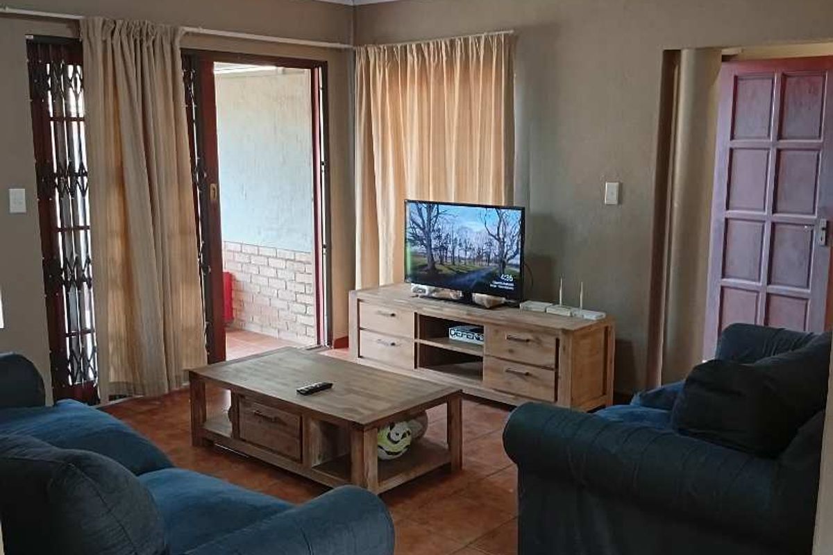 A living room featuring terracotta floor tiles, access to an outdoor patio area, and a traditional wooden door.