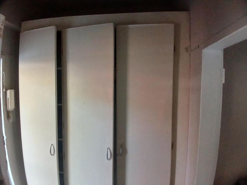 A bedroom featuring built-in cupboards and an intercom system, showing signs of wear and requiring cosmetic updates.