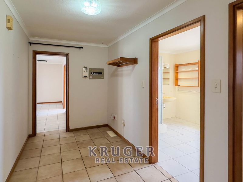 A functional hallway featuring tiled flooring, timber door frames, and access to adjacent rooms, including a bathroom.