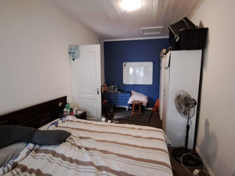 A bedroom featuring a timber panelled ceiling and a loft access hatch, providing a functional space with potential for cosmetic updates.