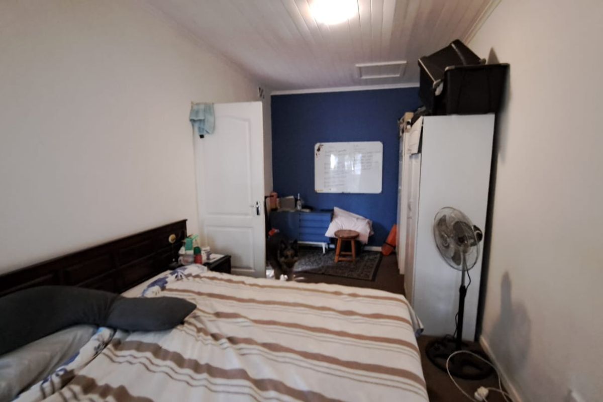 A bedroom featuring a timber panelled ceiling and a loft access hatch, providing a functional space with potential for cosmetic updates.