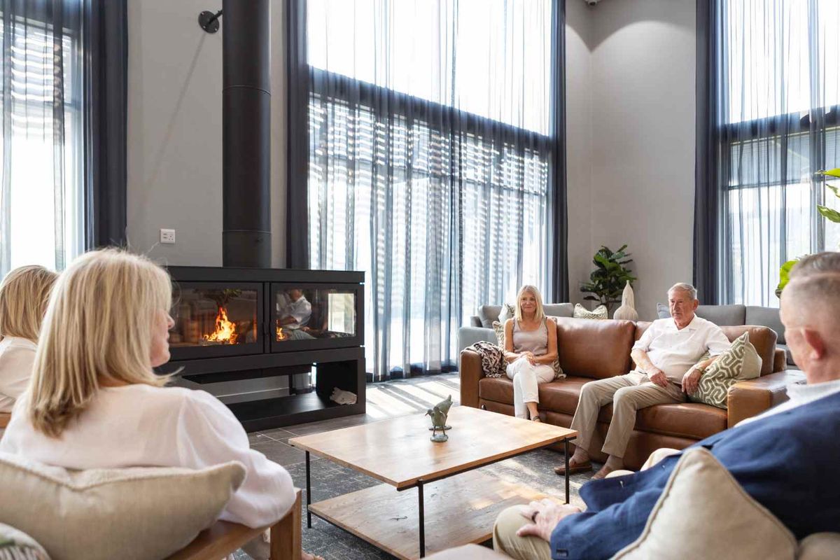 Spacious living room featuring double-height ceilings, floor-to-ceiling windows, and a modern built-in fireplace as a central focal point.