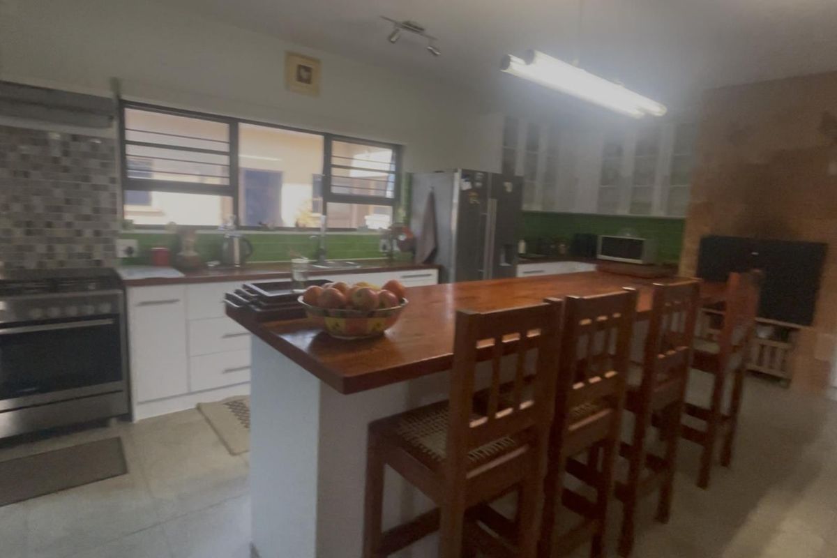 Spacious kitchen featuring a large wooden island, stainless steel gas stove, tiled splashback, and ample built-in cabinetry with a functional layout.