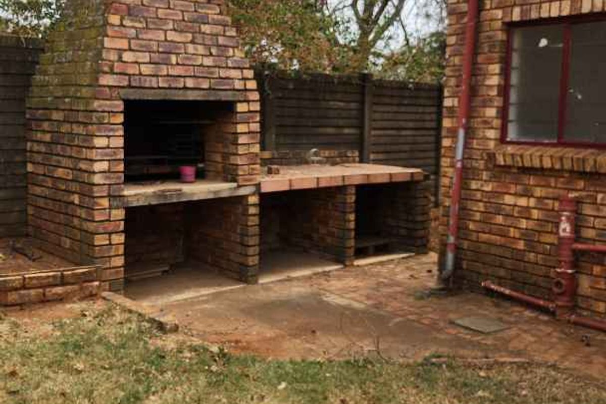 Outdoor entertainment area featuring a built-in brick braai and preparation counter, set against the rear exterior wall of the house.