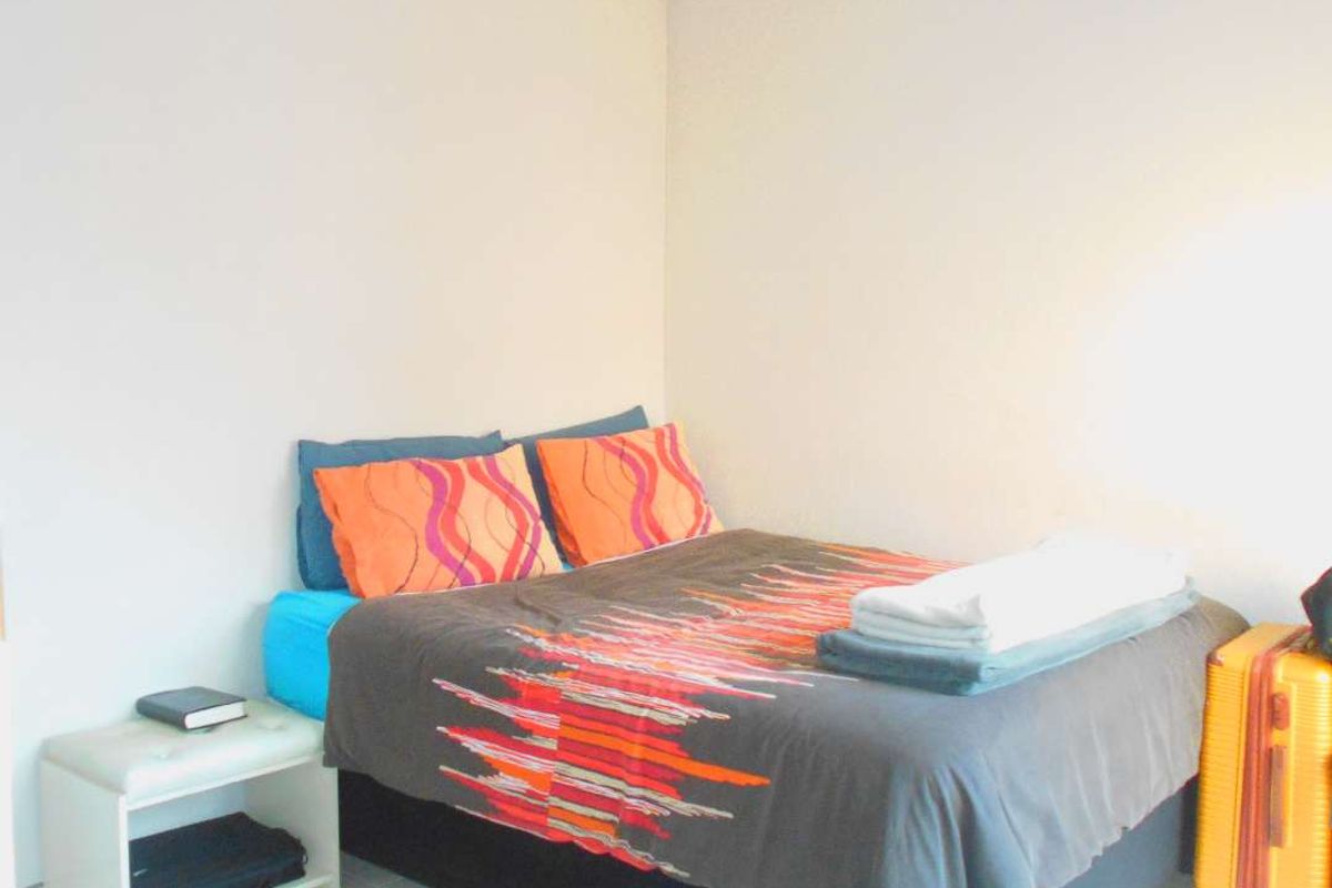 A simple bedroom featuring tiled flooring and neutral wall finishes, providing a functional space for rest.