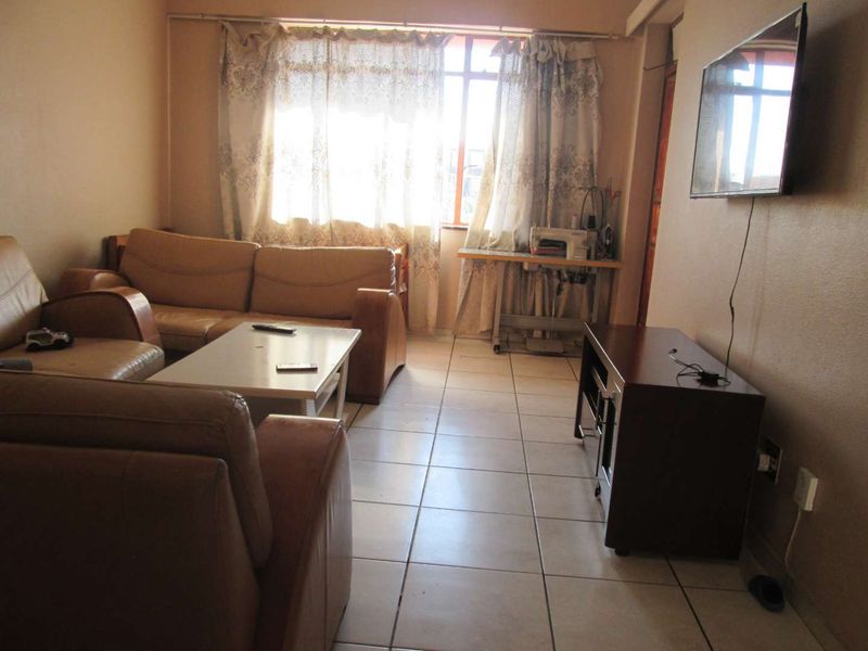 A living room featuring ceramic floor tiles and a large window, providing a functional space with potential for modern updates.