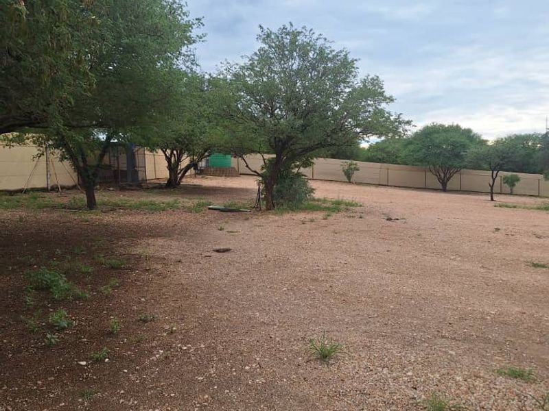 A spacious, open industrial rear yard area featuring gravel ground cover, perimeter fencing, and a partial shade sail structure.