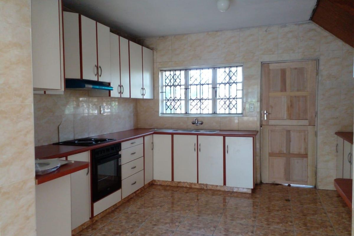 A functional kitchen featuring built-in cabinetry, laminate countertops, a built-in oven with hob, and tiled finishes throughout.