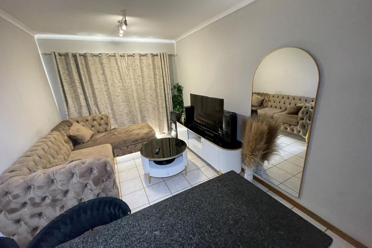 A well-maintained living room featuring tiled flooring, ceiling coving, and track lighting, creating a comfortable and functional space.