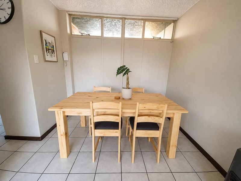 A dining area featuring neutral walls, ceramic floor tiles, and high-level clerestory windows providing natural light.