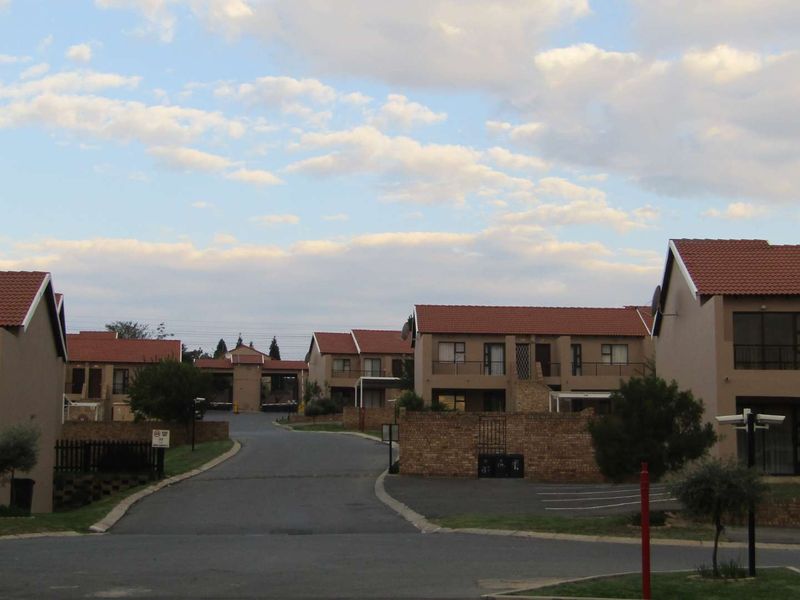 A view of the apartment complex featuring multiple residential units with tiled roofs, paved driveways, and established communal grounds.