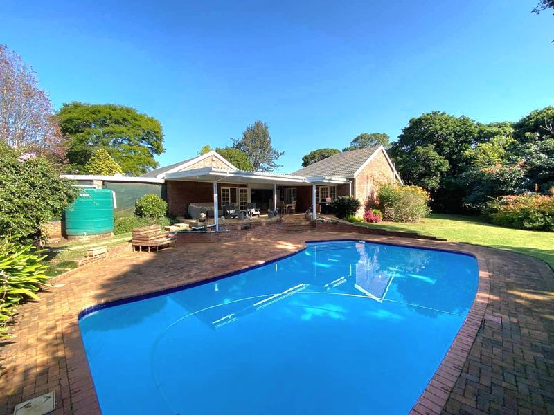Spacious backyard featuring a large swimming pool, brick paved surround, and a covered patio area perfect for outdoor entertaining.