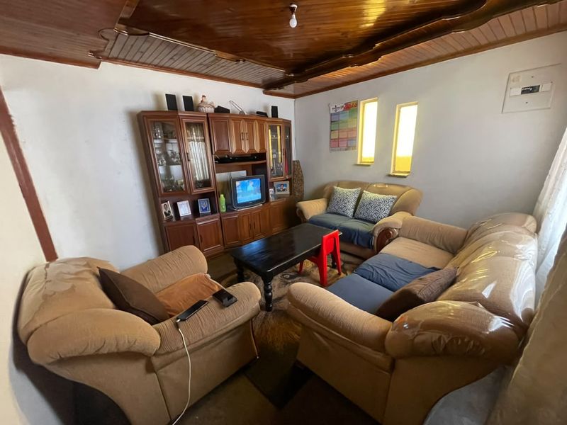 A living room featuring a distinctive timber tongue and groove ceiling and standard wall finishes, offering a functional space for relaxation.