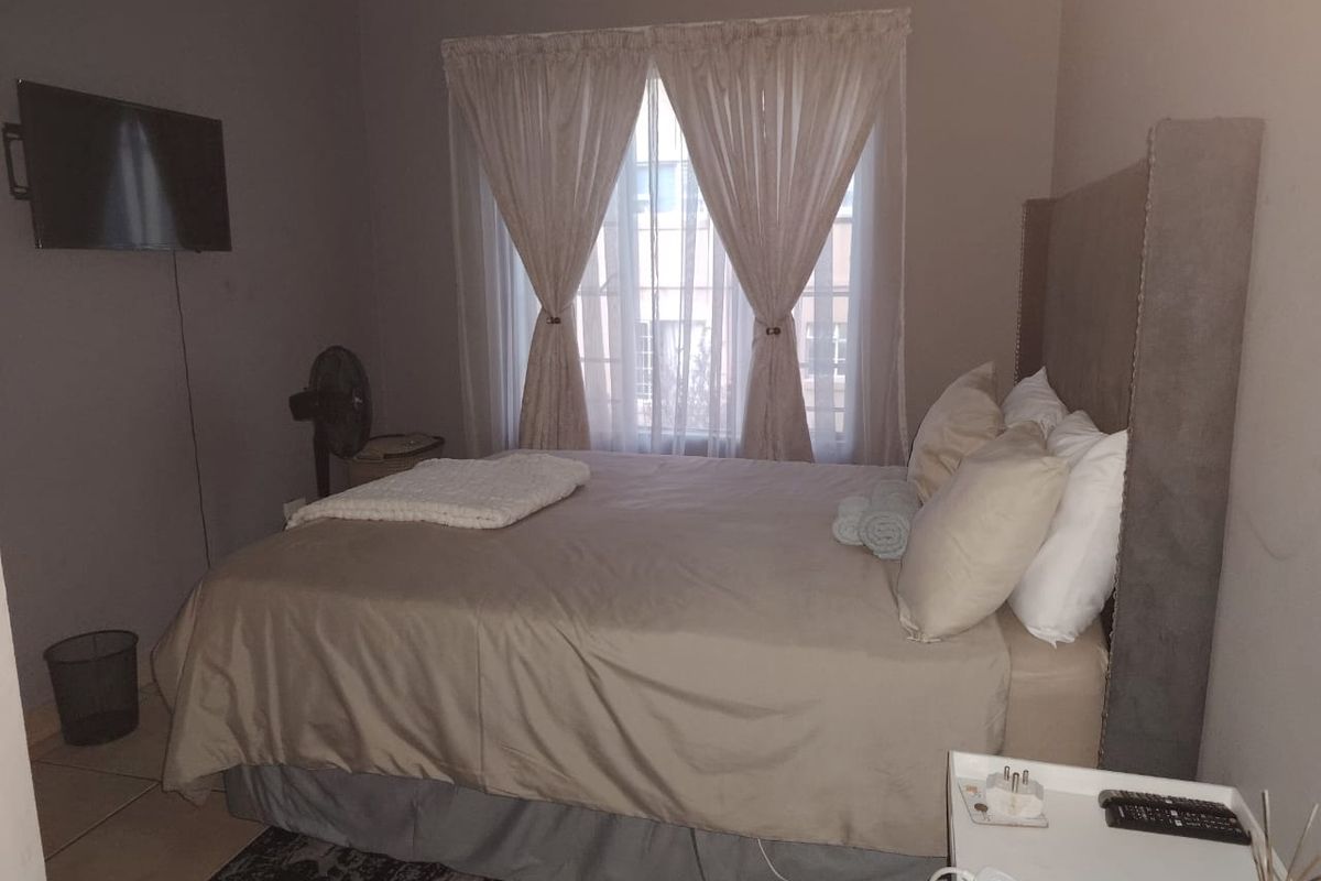 A standard bedroom featuring tiled flooring and a window with curtains, providing a functional and neutral living space.