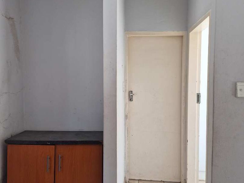 A functional hallway area featuring tiled flooring, built-in cabinetry, and access to adjacent rooms, showing signs of wear on the wall finishes.