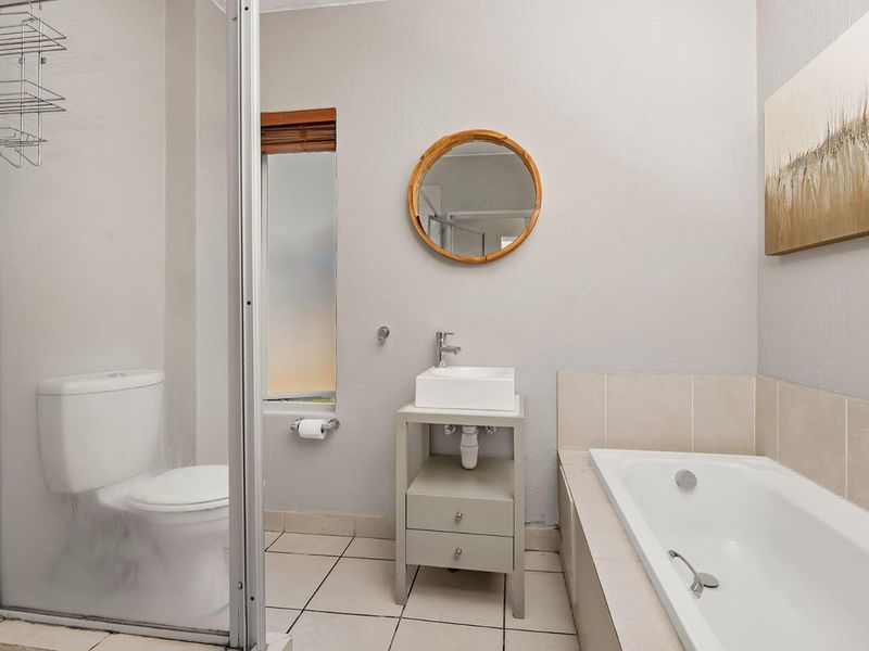 A functional bathroom featuring a shower enclosure, a built-in bathtub, a modern basin with vanity storage, and tiled flooring.