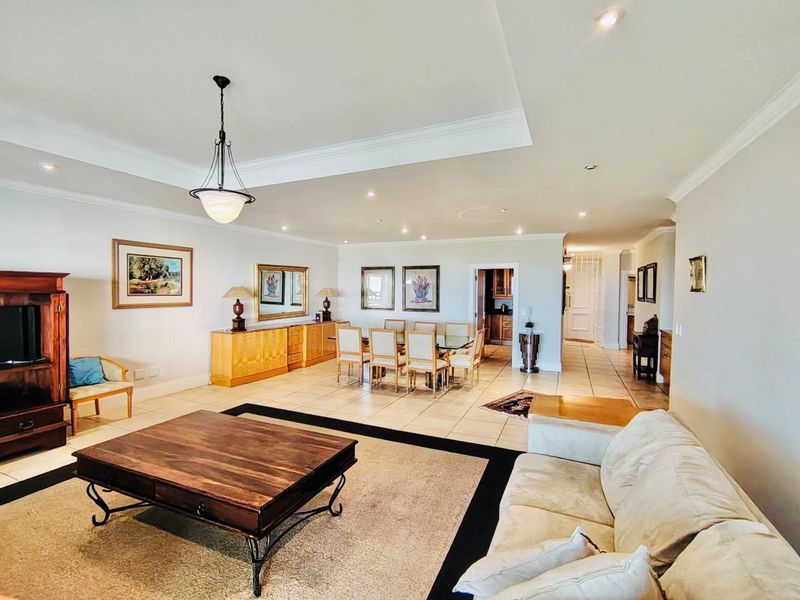 Spacious open-plan living and dining area featuring neutral tiled flooring, recessed lighting, and a coved ceiling, creating a bright and versatile living space.