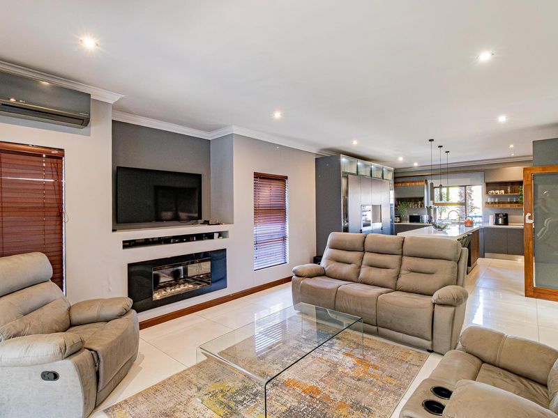 Spacious open-plan living area featuring a modern kitchen with island, built-in fireplace, and sleek tiled flooring throughout.