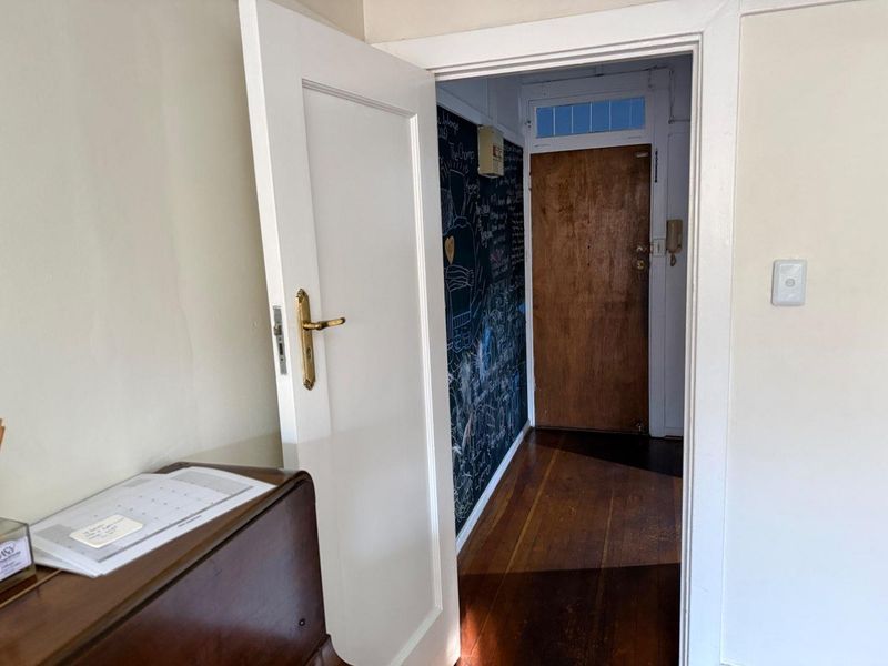 An entry area featuring original timber flooring, a solid wood front door with a transom window, and an integrated intercom system.