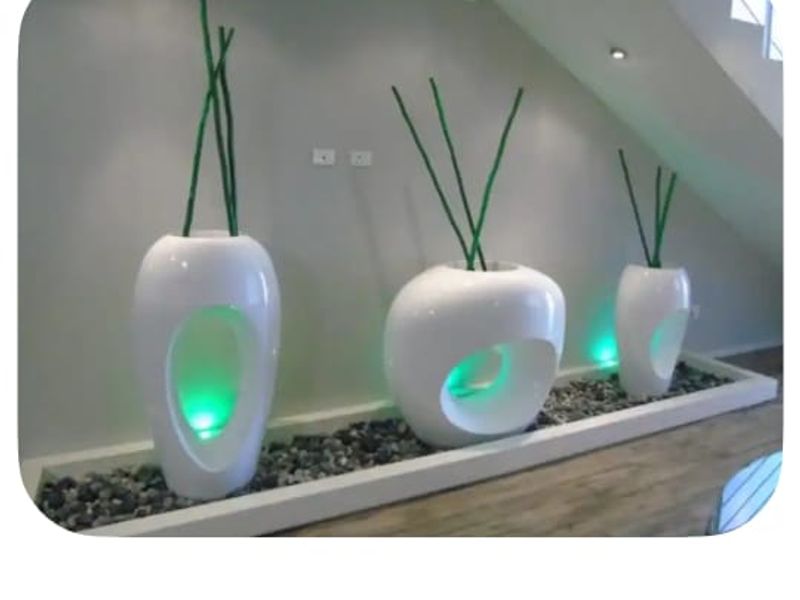 A modern hallway area featuring a decorative stone-filled floor recess beneath a staircase, illuminated by recessed lighting.