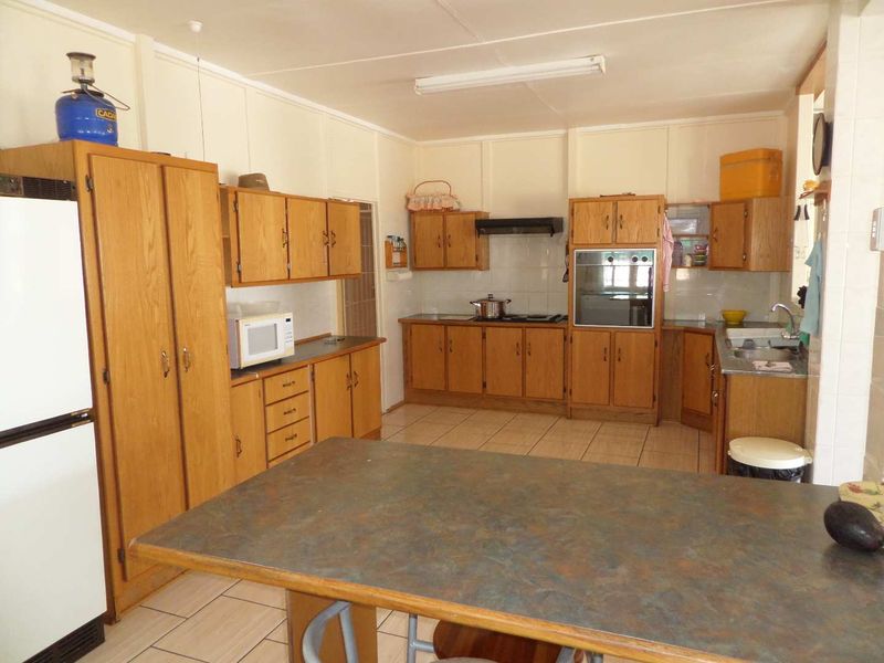 A functional kitchen featuring traditional wooden cabinetry, laminate countertops, built-in oven, and tiled flooring, offering a classic layout with ample storage space.
