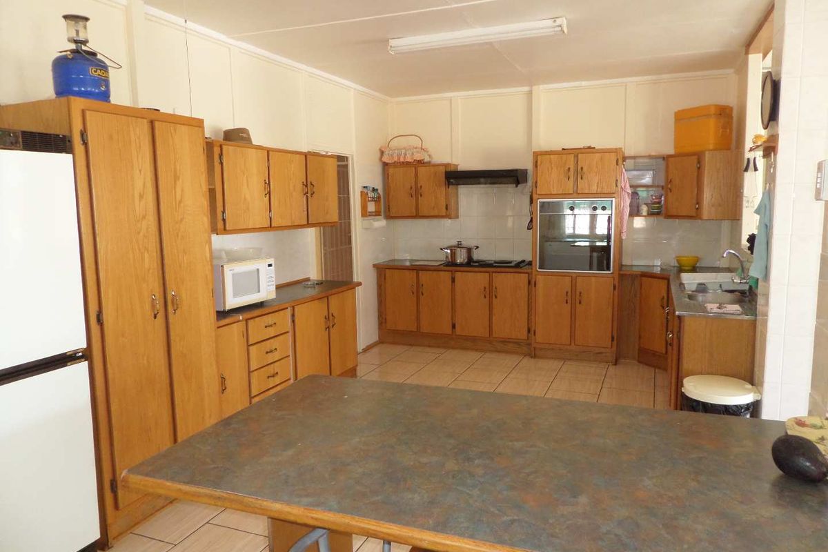 A functional kitchen featuring traditional wooden cabinetry, laminate countertops, built-in oven, and tiled flooring, offering a classic layout with ample storage space.