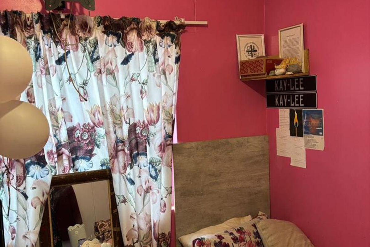 A bedroom featuring a built-in headboard and wall-mounted television bracket, currently finished with vibrant pink wall paint.