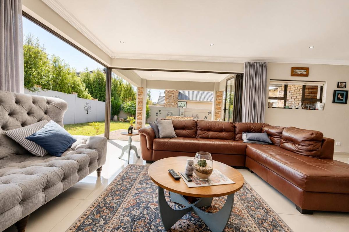 Spacious living room featuring large sliding glass doors that open to an outdoor patio, tiled floors, and recessed lighting.