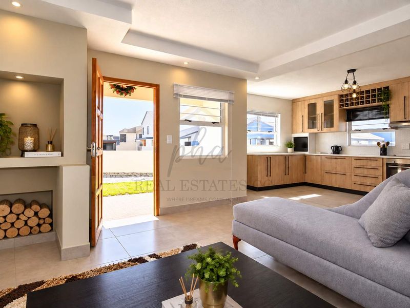 Modern open-plan living area featuring a well-appointed kitchen with light wood cabinetry, recessed lighting, and seamless flow to the outdoor entrance.