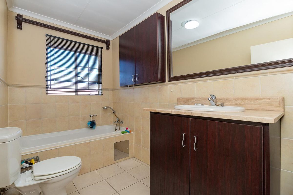 A functional bathroom featuring a built-in bathtub, tiled walls, a vanity with storage, and a large wall-mounted mirror.