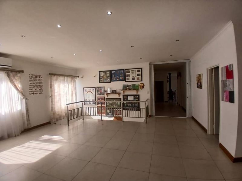 Spacious open-plan living area featuring tiled flooring, recessed downlighting, and a metal balustrade, offering a versatile layout for various living arrangements.