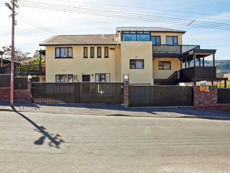 Front elevation of a multi-level residential property featuring a secure gated entrance, balcony, and tiled roof structure.