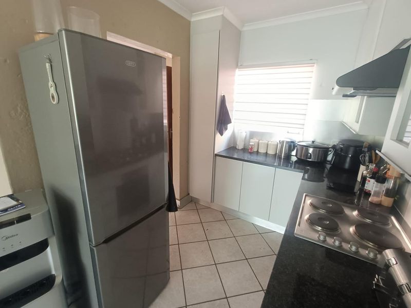 Functional kitchen featuring granite countertops, built-in cabinetry, an electric hob with extractor fan, and tiled flooring.