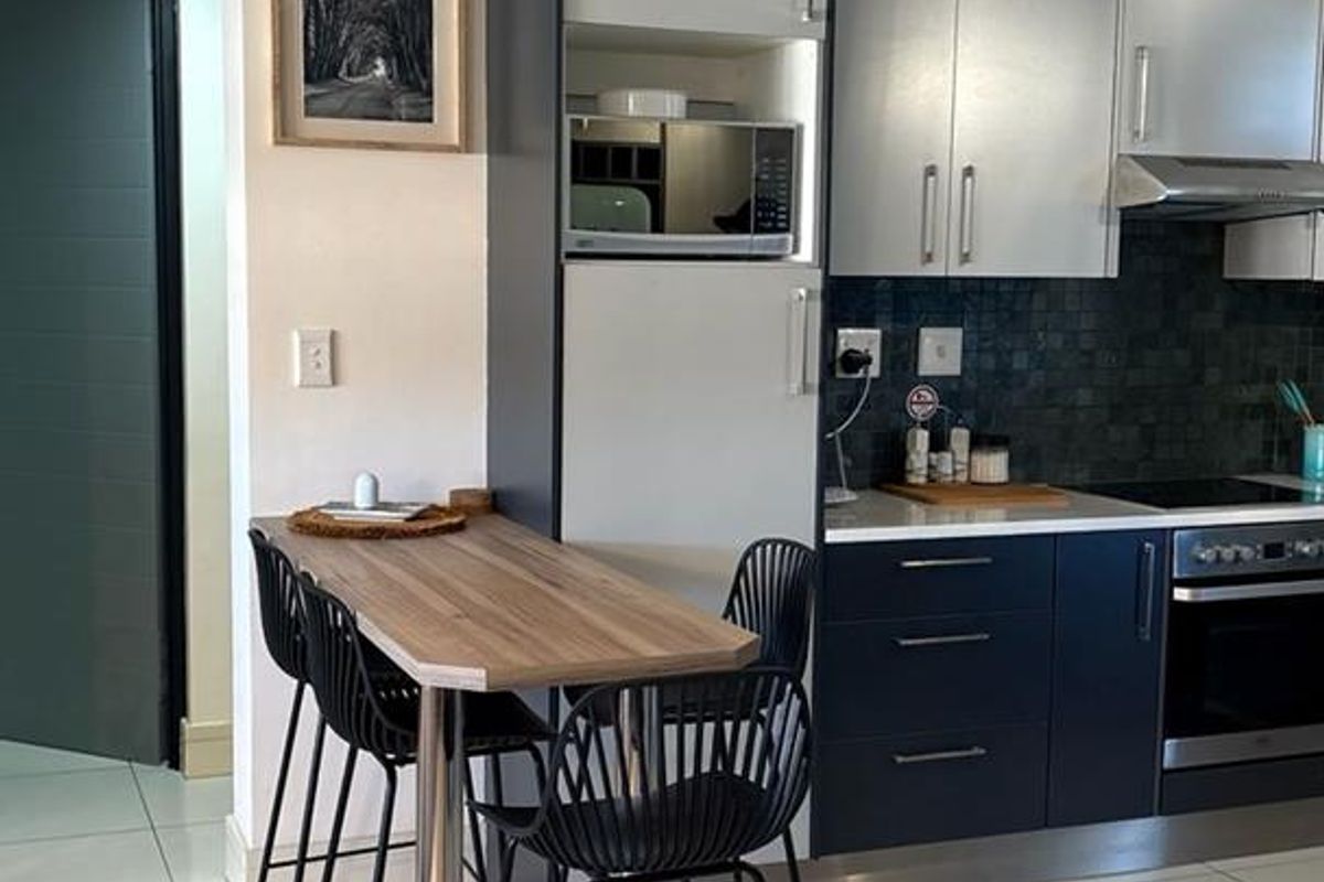 Modern kitchen featuring two-tone cabinetry, built-in appliances, mosaic tile backsplash, and polished floor tiles with an integrated breakfast bar.