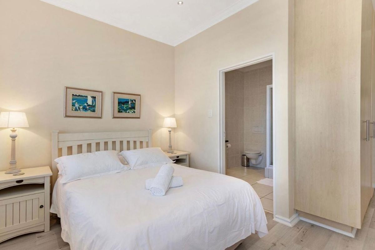 A well-maintained bedroom featuring built-in wooden cabinetry and an en-suite bathroom with tiled finishes.