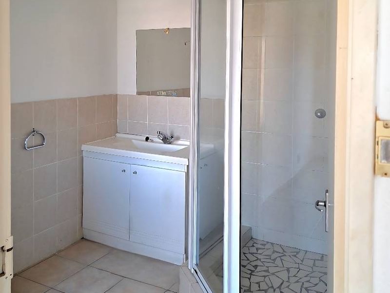 A functional bathroom featuring a vanity cabinet, basin, and a corner shower enclosure with tiled finishes.