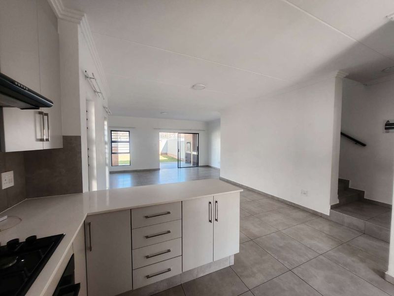 Spacious open-plan kitchen and living area featuring modern cabinetry, tiled floors, and direct access to the rear patio through sliding glass doors.
