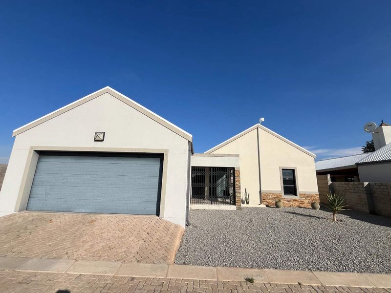 Front elevation of a residential property featuring a double garage, stone cladding accents, and a low-maintenance gravel garden.