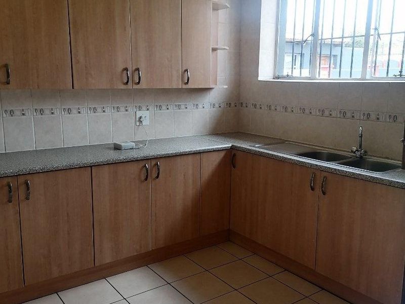 A functional kitchen featuring laminate cabinetry, granite-look countertops, a double bowl stainless steel sink, and ceramic tile flooring.