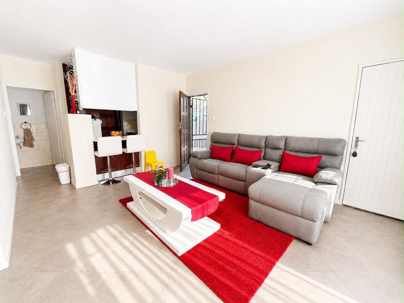 Open plan living area featuring tiled flooring, a breakfast bar, and direct access to a security gate.