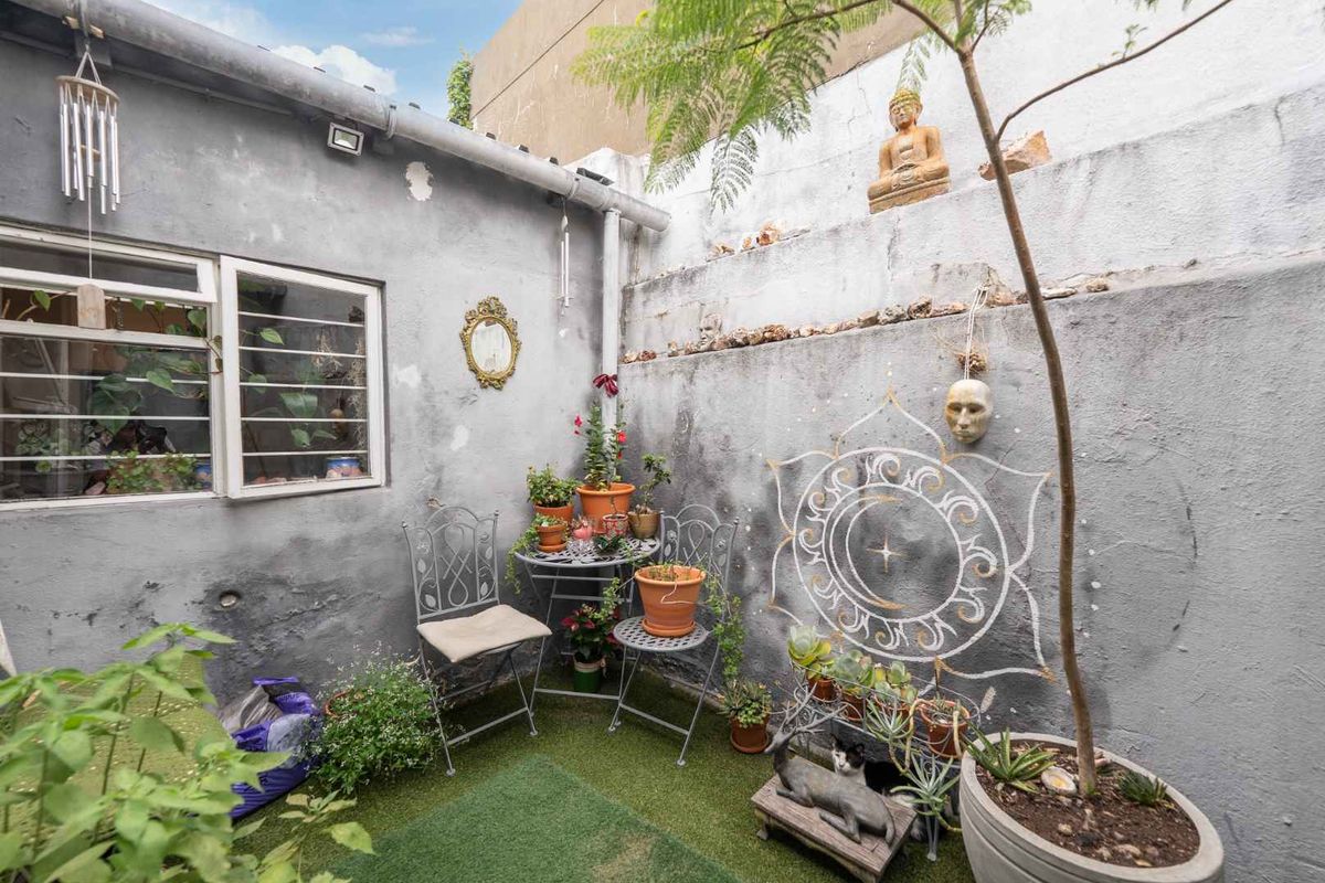 A small, enclosed rear courtyard featuring rendered masonry walls with visible weathering and security-barred windows.