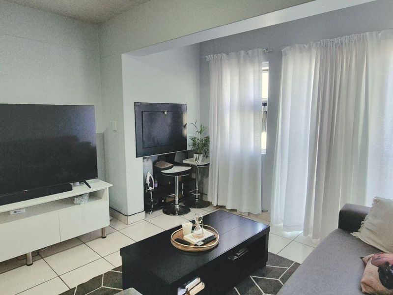 A living room area featuring tiled flooring and a sliding glass door providing access to an outdoor space.