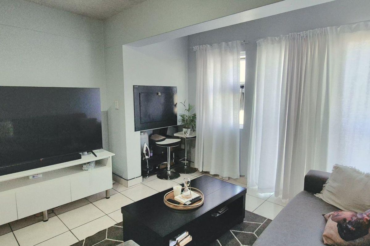 A living room area featuring tiled flooring and a sliding glass door providing access to an outdoor space.
