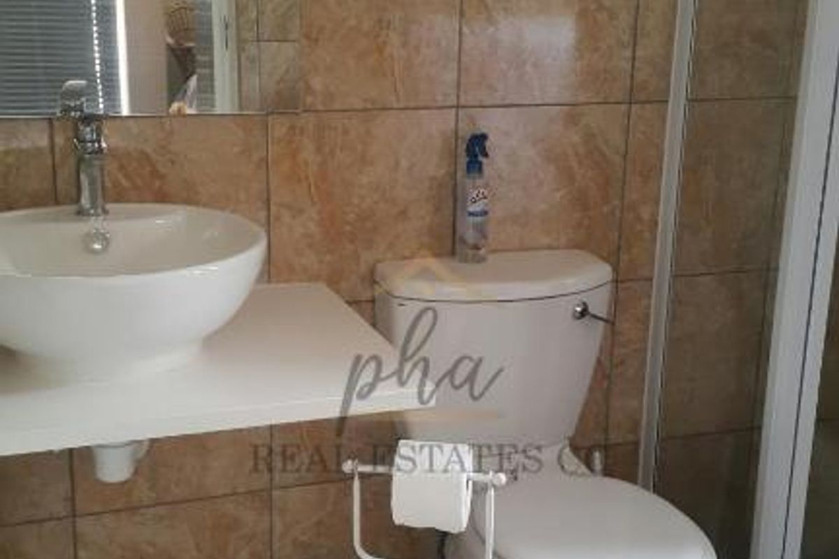 A functional bathroom featuring a vessel sink, wall-mounted vanity, toilet, and a glass-enclosed shower with floor-to-ceiling tiled walls.