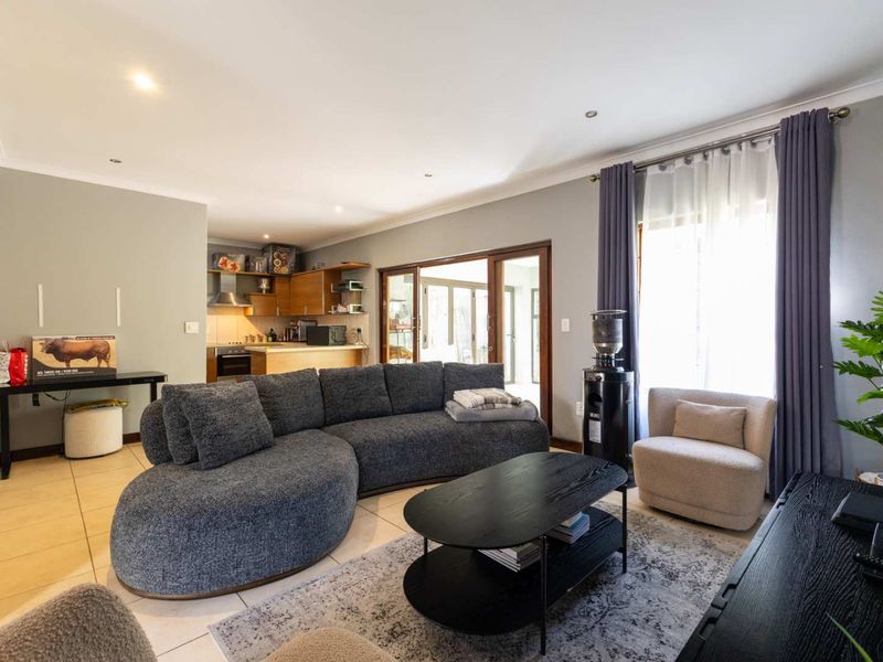 Spacious open-plan living area featuring tiled floors, recessed lighting, and seamless flow to the kitchen and outdoor patio through sliding glass doors.