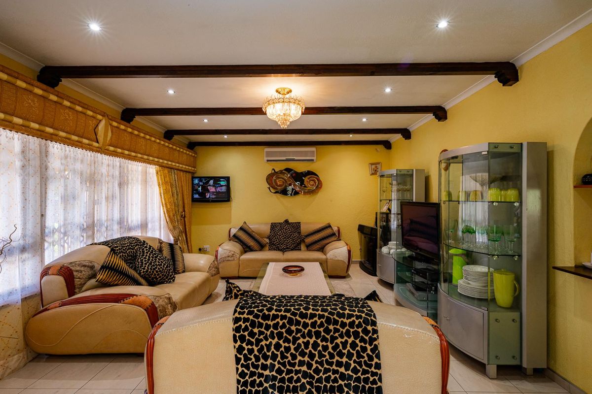 A comfortable living room featuring exposed timber ceiling beams, recessed downlighting, and a wall-mounted air conditioning unit.